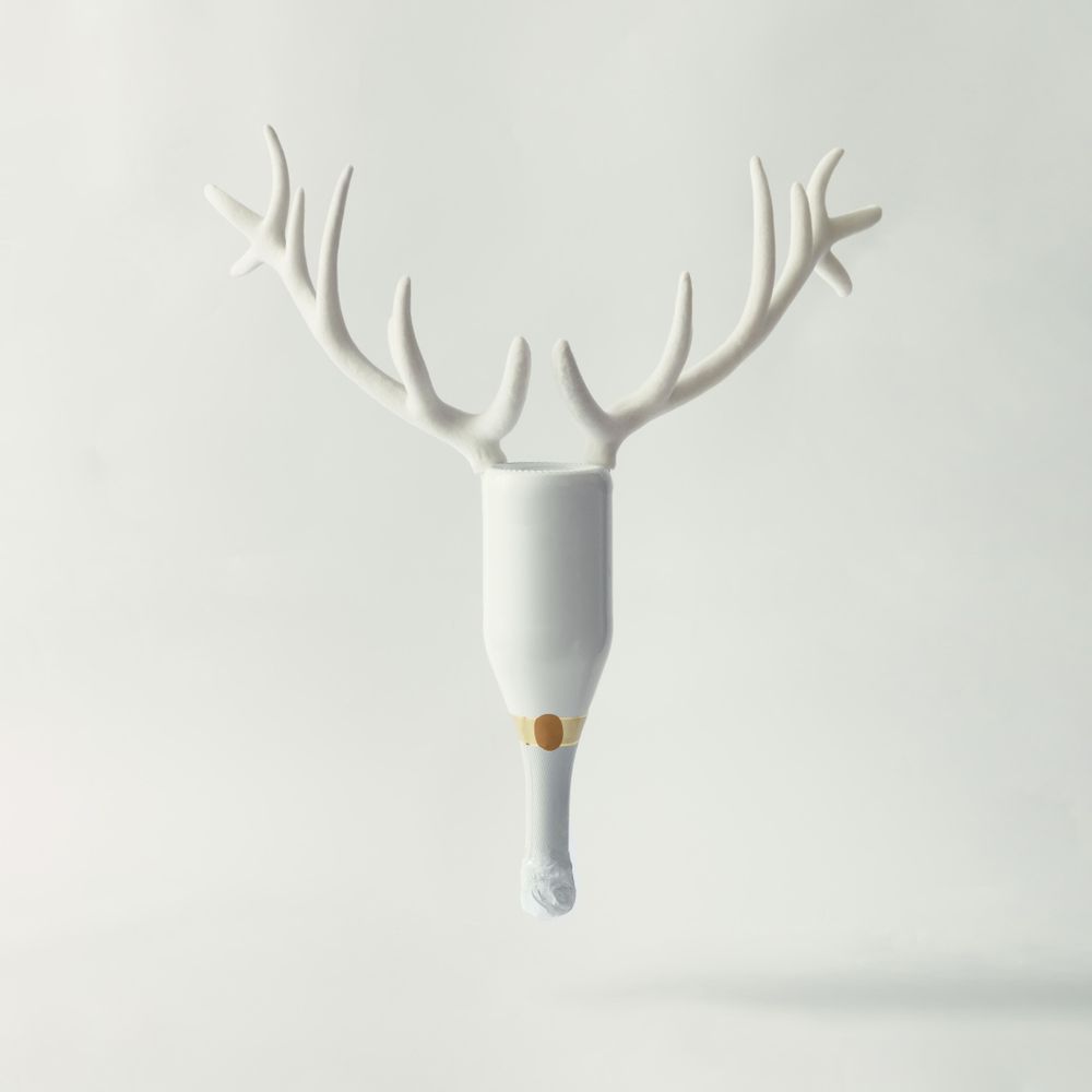 Champagne bottle with reindeer antlers on bright background