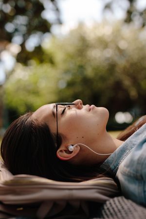 Woman relaxing outdoors listening to music with earphones