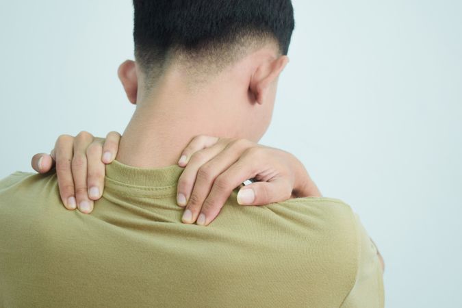 Asian young man touching back of neck in pain