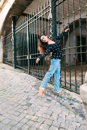 Casual woman dancing on old city street