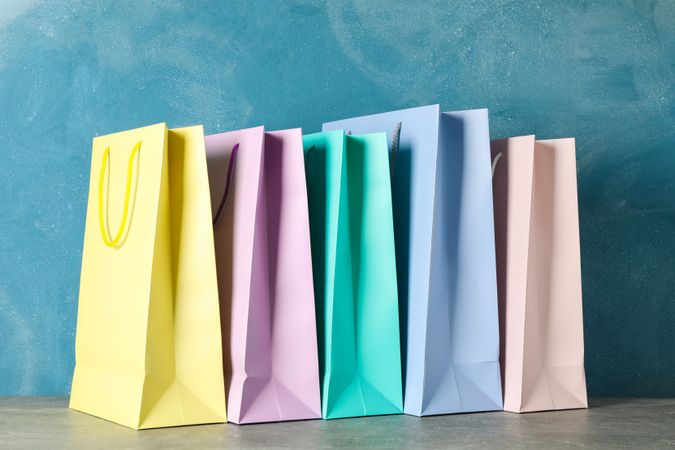 Color bags on grey table against blue background, copy space
