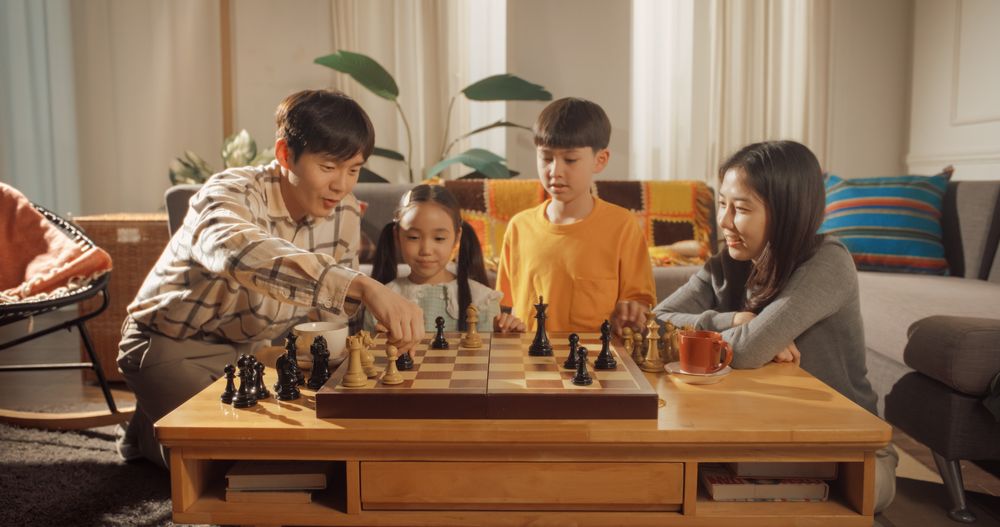 Close Up of a Game of Chess Between Young Father and his Son at Home.
