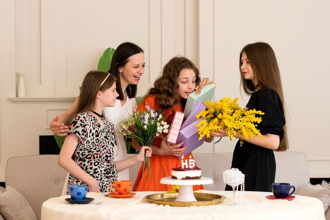Family gathered around girl opening birthday gift