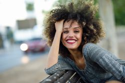 Joyful female in casual dress sitting on park bench
