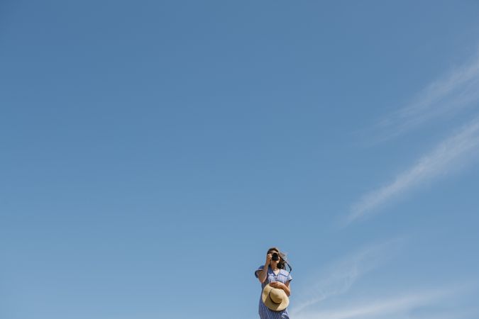 Traveling young female taking photo against blue sky