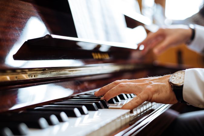 Crop male hands playing piano