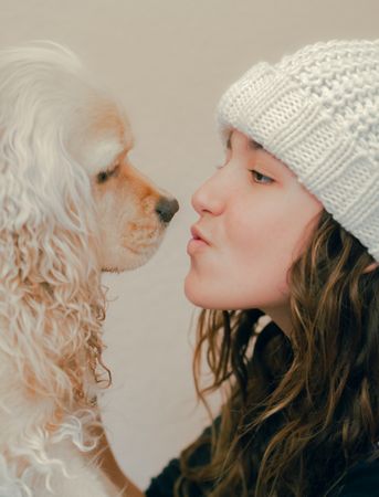 Teen in hat playing with dog