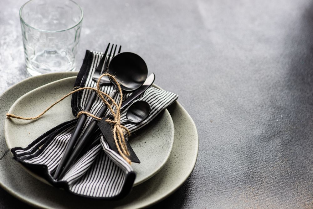 Table setting with dark cutlery & string on concrete background with copy space