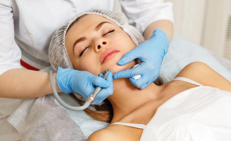 Woman having facial beauty treatment with machine on her chin