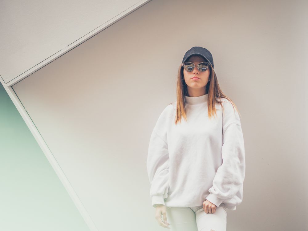 Young woman with glasses standing against wall