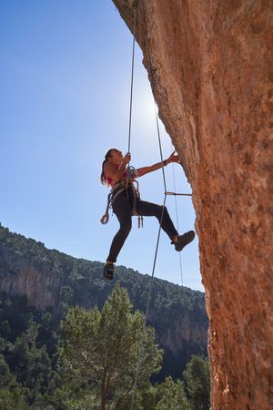 Female alpinist hanging from cliff on dynamic rope