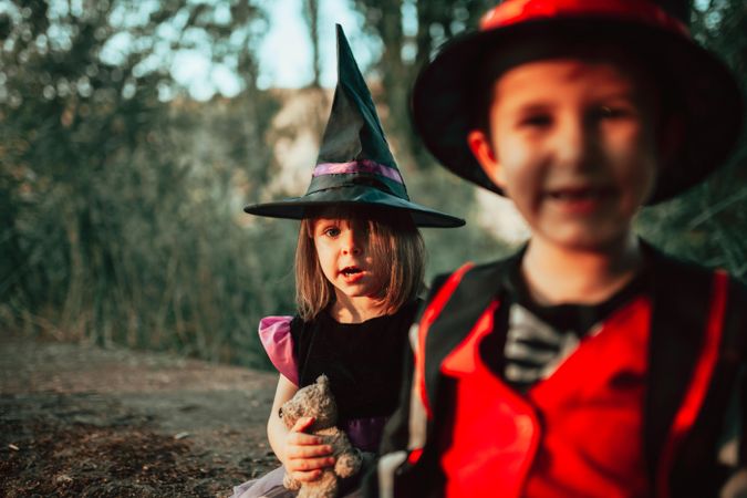 Two siblings in the forest dressed in halloween costumes