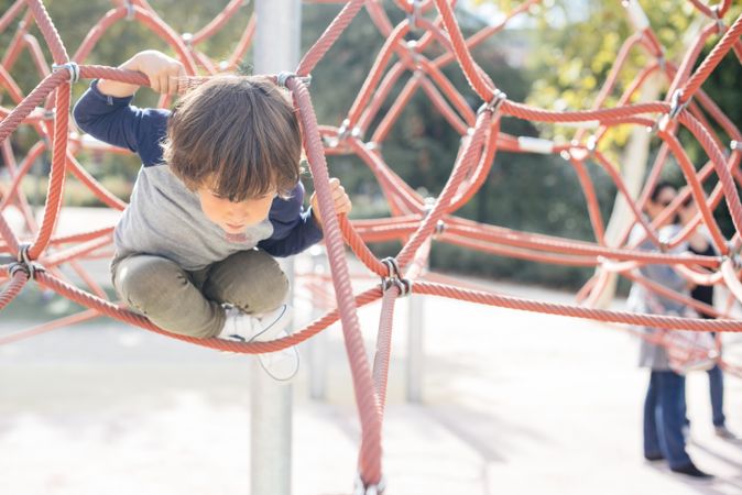 Boy on rope climbing net in sunlight