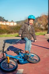 Distressed boy kicking bike in frustration after falling