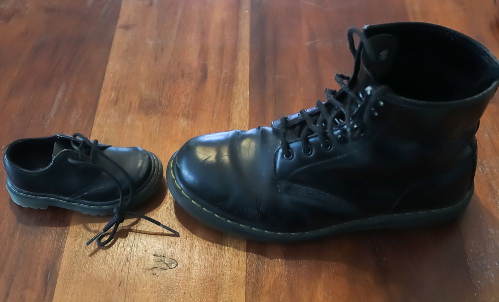 Big and small old leather shoe on a wooden floor