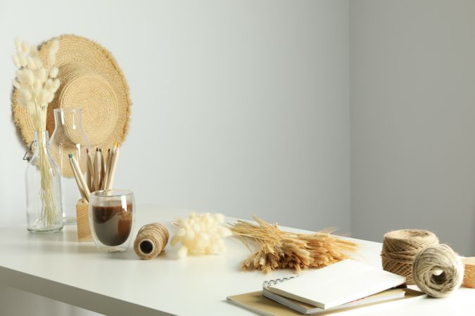 Work table with yarn, notebooks, pencils, dried flowers, with hat and copy space