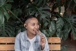 A young Hispanic woman is enjoying an ice cream while listening to music