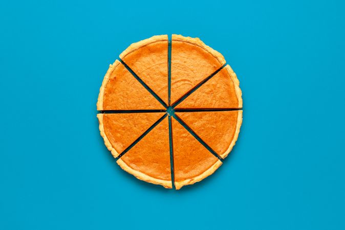 Sliced pumpkin pie top view, on a blue table
