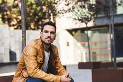 Stylish man sitting outside modern building