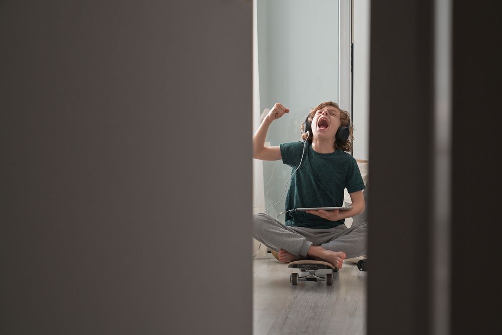 Expressive boy sitting on skateboard and watching video