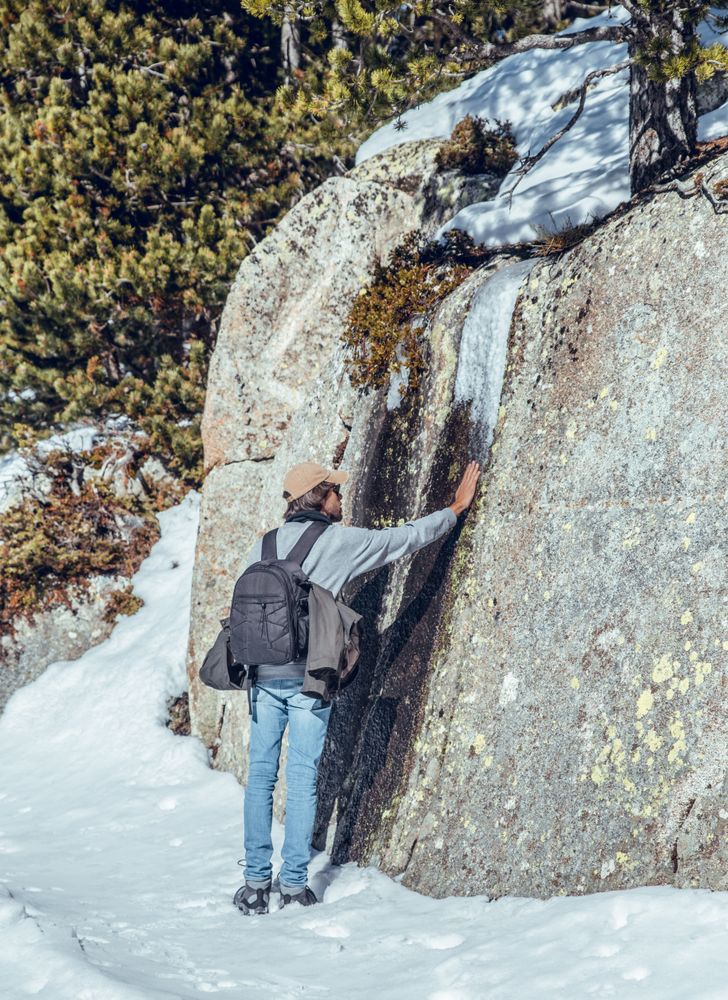 Man touching stone near trees in winter