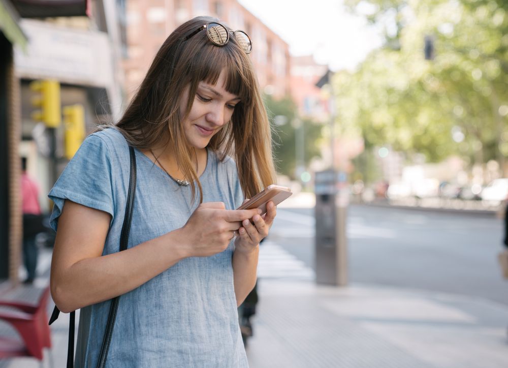 Woman with glasses using smartphone outdoor