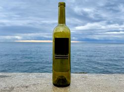 Bottle of wine on wall overlooking the sea