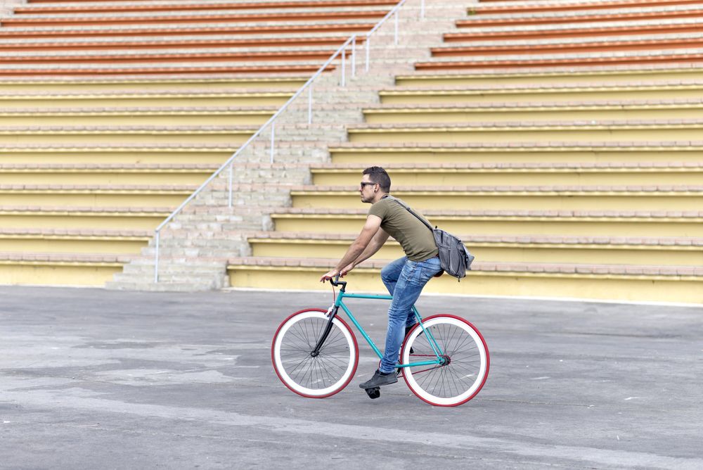 Male on bicycle with yellow outdoor seating in background