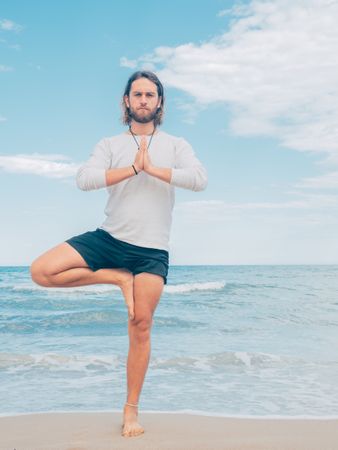 Man training yoga on beach