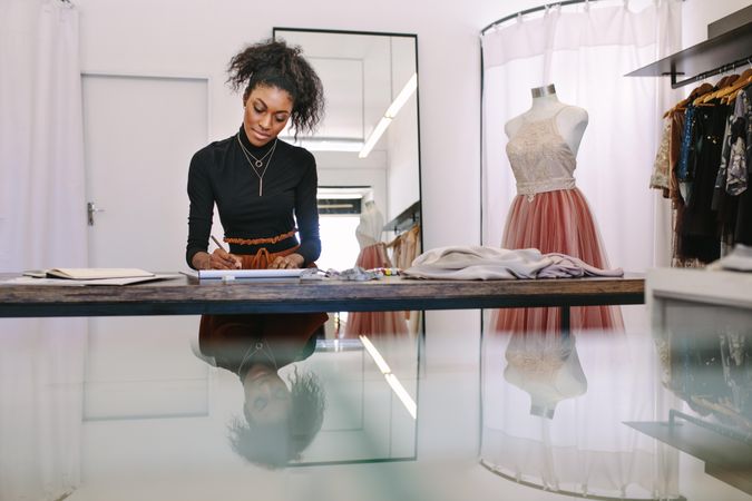 Stylish fashion designer sketching a design sitting at her studio desk