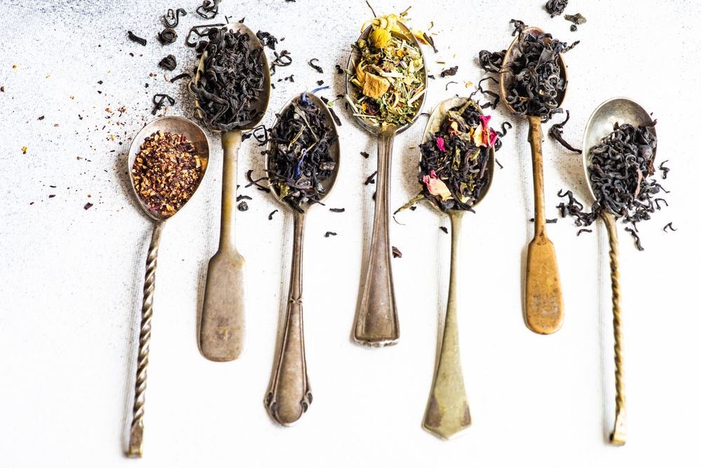 Vintage spoons with loose leaf tea on counter