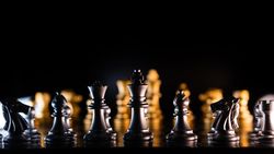 Silhouetted chess pieces on illuminated board