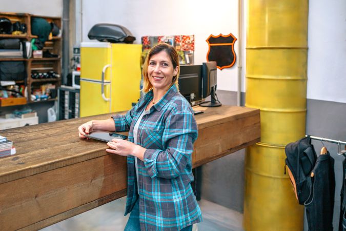 Portrait of happy young woman owner standing in front of store counter with copy space