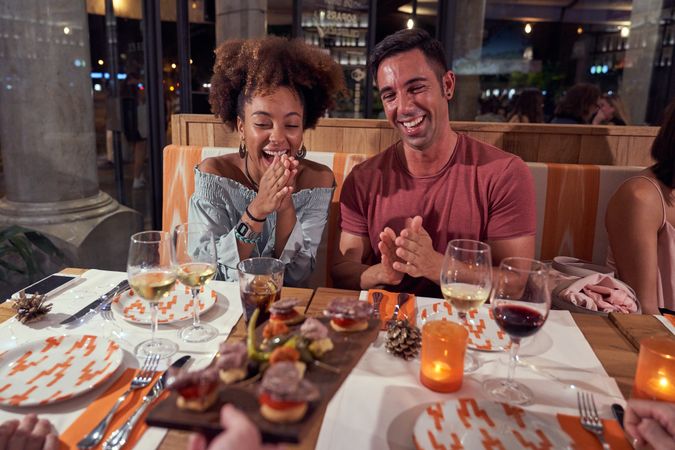Joyful multiracial friends at served table