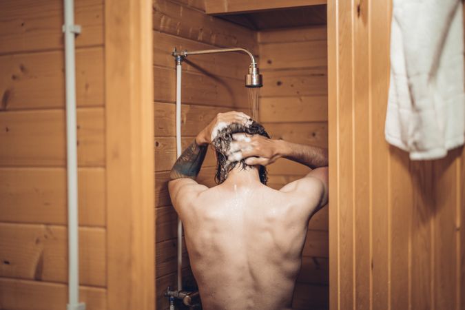 Man taking shower in wooden bathroom