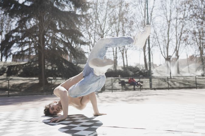 Shirtless man dancing break dance in park