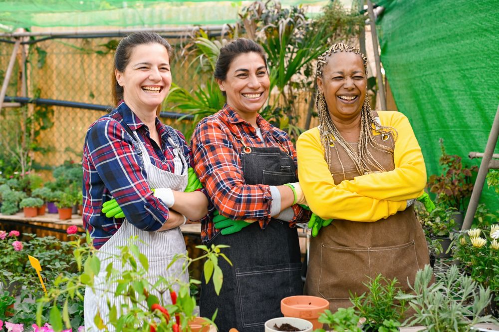 Positive multiracial farmers standing near table in garden