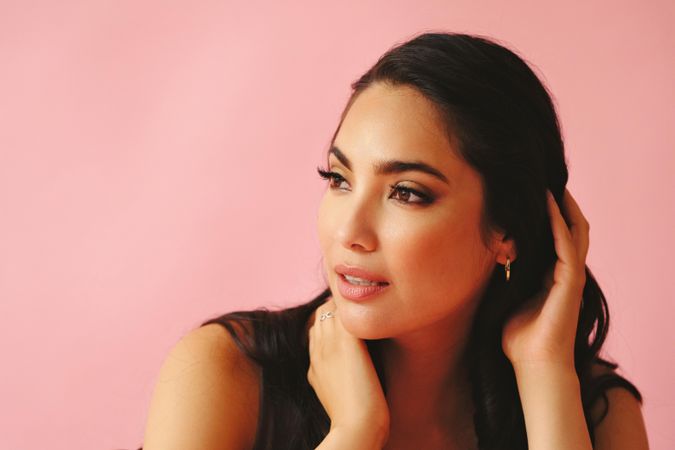 Wistful Hispanic woman looking away from camera in pink room