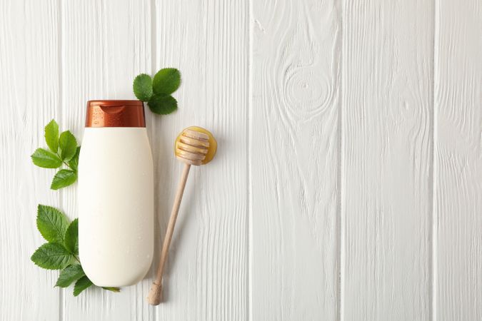 Natural hair care. Blank shampoo bottle and natural ingredients on wooden background