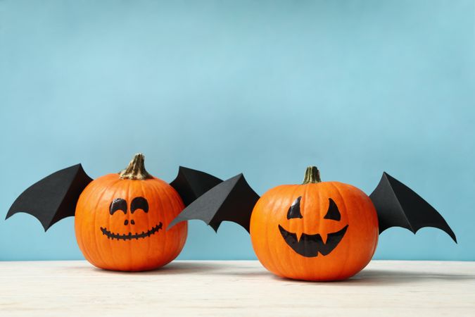 Pumpkins with smile and wings on blue background