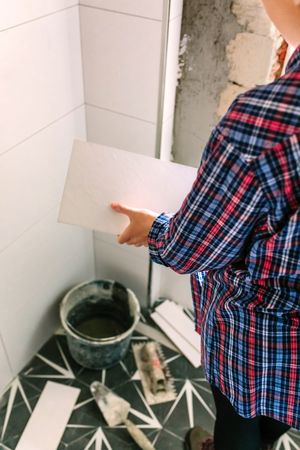 Female bricklayer taking a tile to bathroom renovation