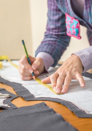 Dressmaker drawing tailor pattern on the table