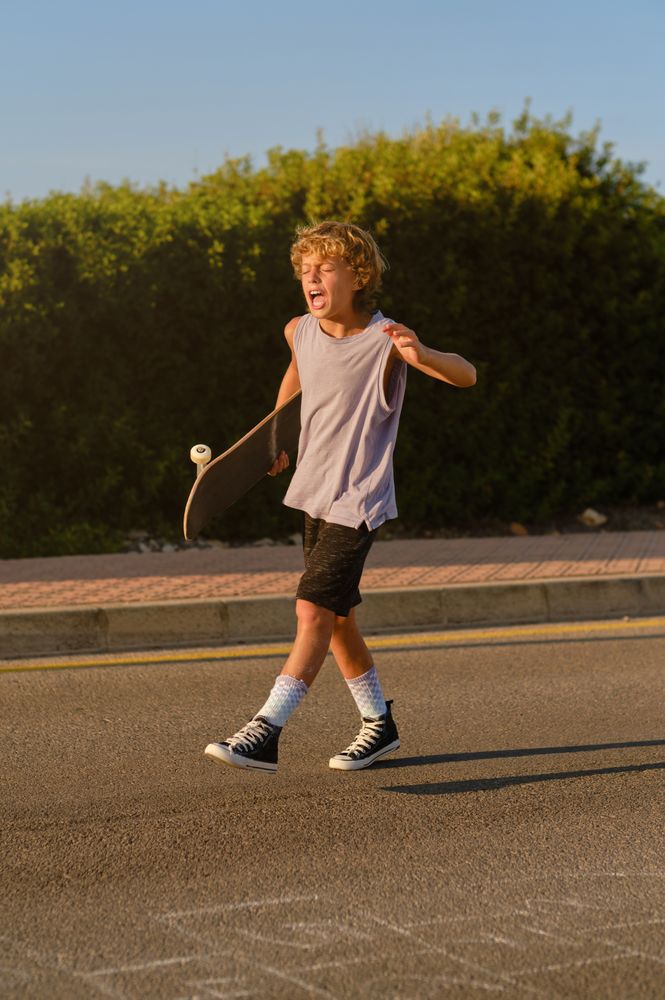 Expressive skater walking with skateboard along road