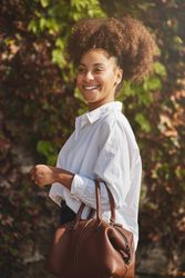 Black woman standing near green bush on street