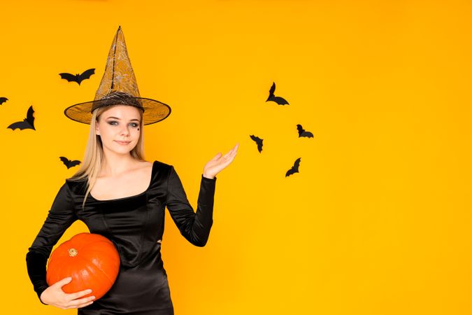 A woman in a Halloween costume with a pumpkin in her hands