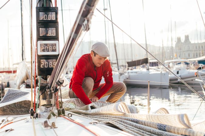 Sailor on yacht arranging the covering at sunset