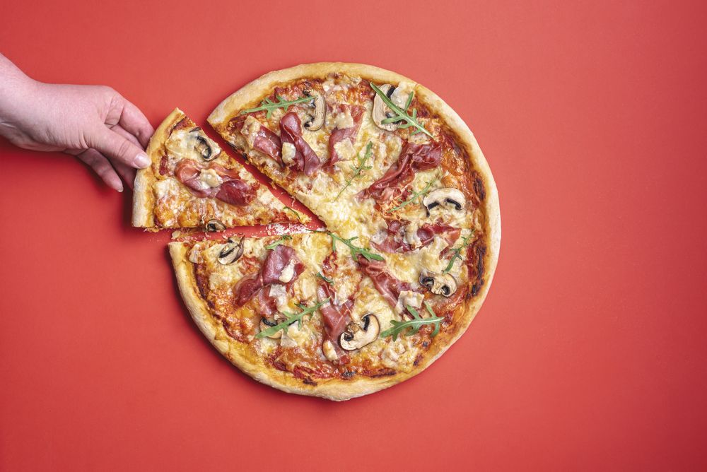 Woman grabbing a slice of pizza to eat