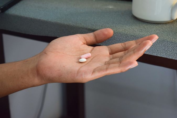 Hand of person with two pills in palm