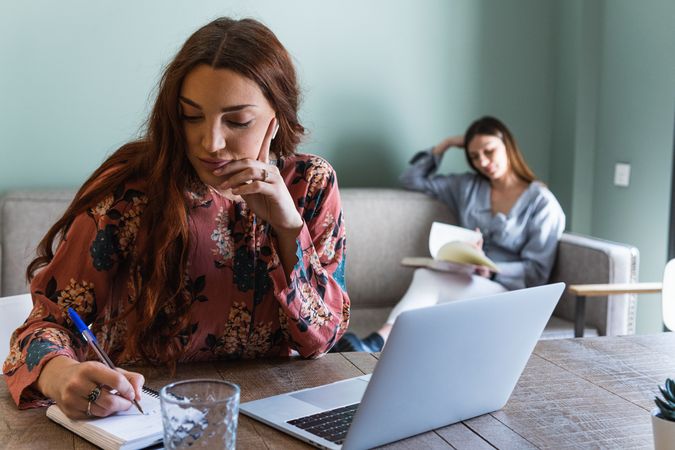 Focused woman taking notes and working on laptop