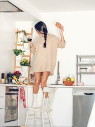 Excited female dancing on chair with coffee